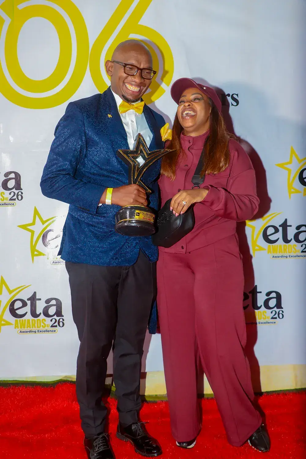 Two guests with the ETA Awards trophy on the red carpet