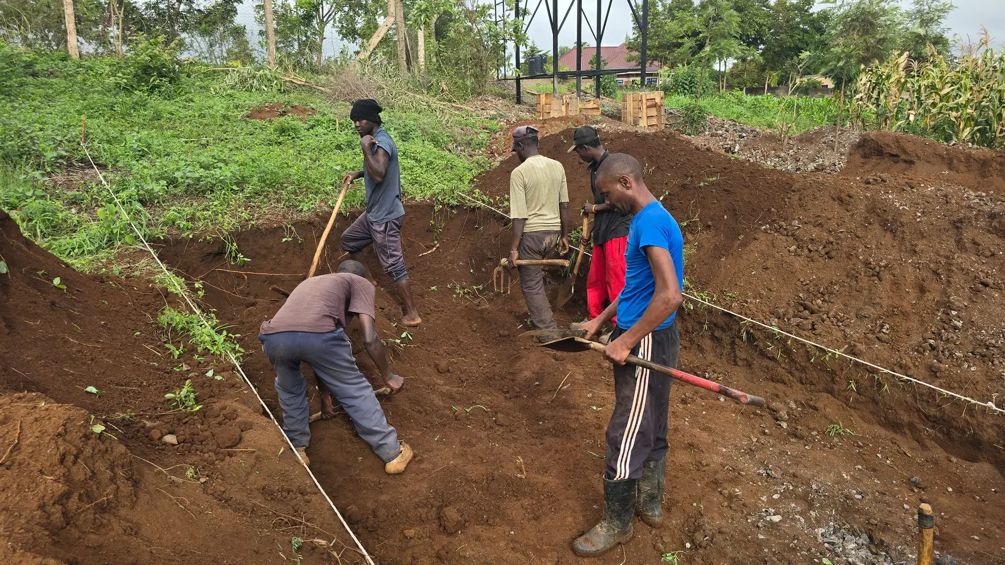 A team of young people digging and levelling ground with jembes at Moran Farms