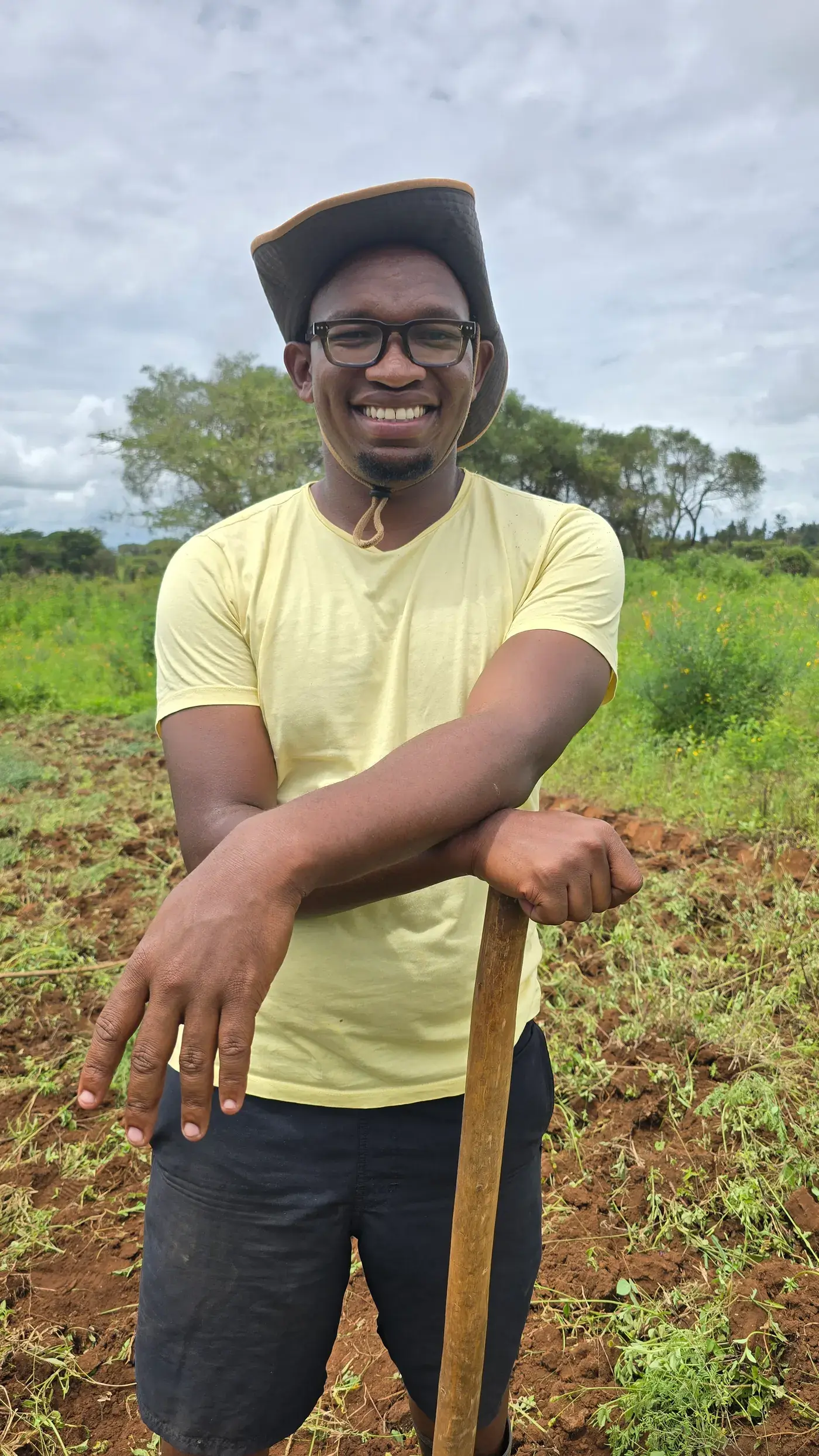 Siloma Stephen, founder of Moran Farms, leaning on a hoe in a newly prepared field